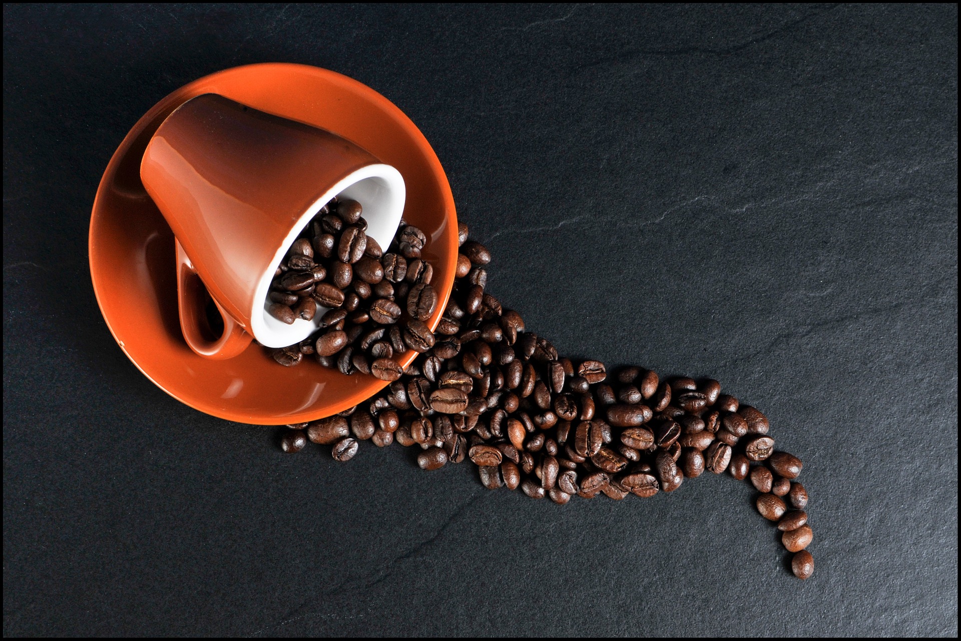A cup fallen over with spilled coffee beans